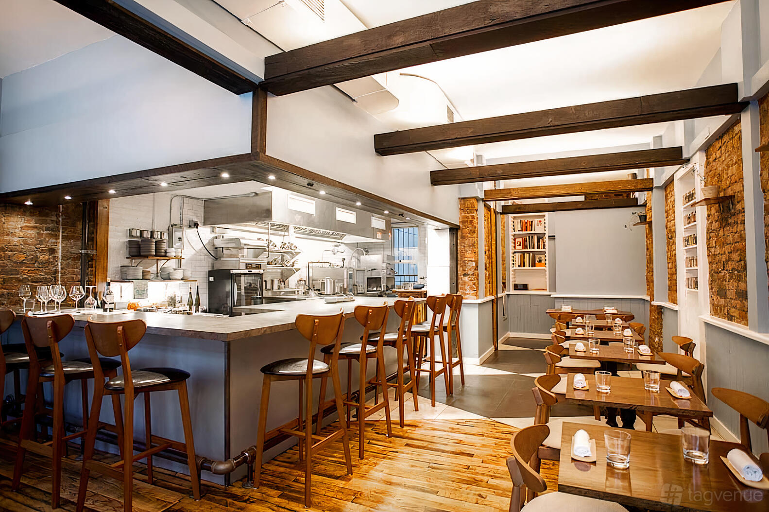 A restaurant with exposed brick columns, wooden ceiling beams, and an open kitchen counter at Luthun.