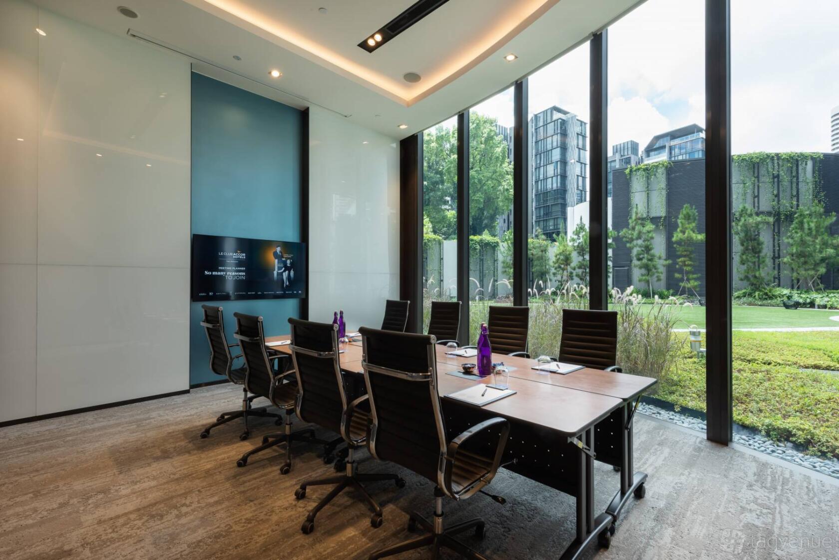 A function room with floor-to-ceiling windows, boardroom setup, and garden views at Novotel Singapore on Stevens.