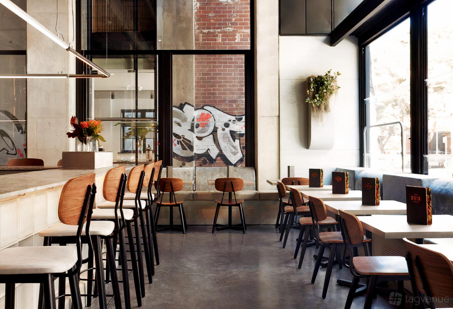 A winery with floor-to-ceiling windows, high-top bar seating, and wood chairs at Brix Distillery.