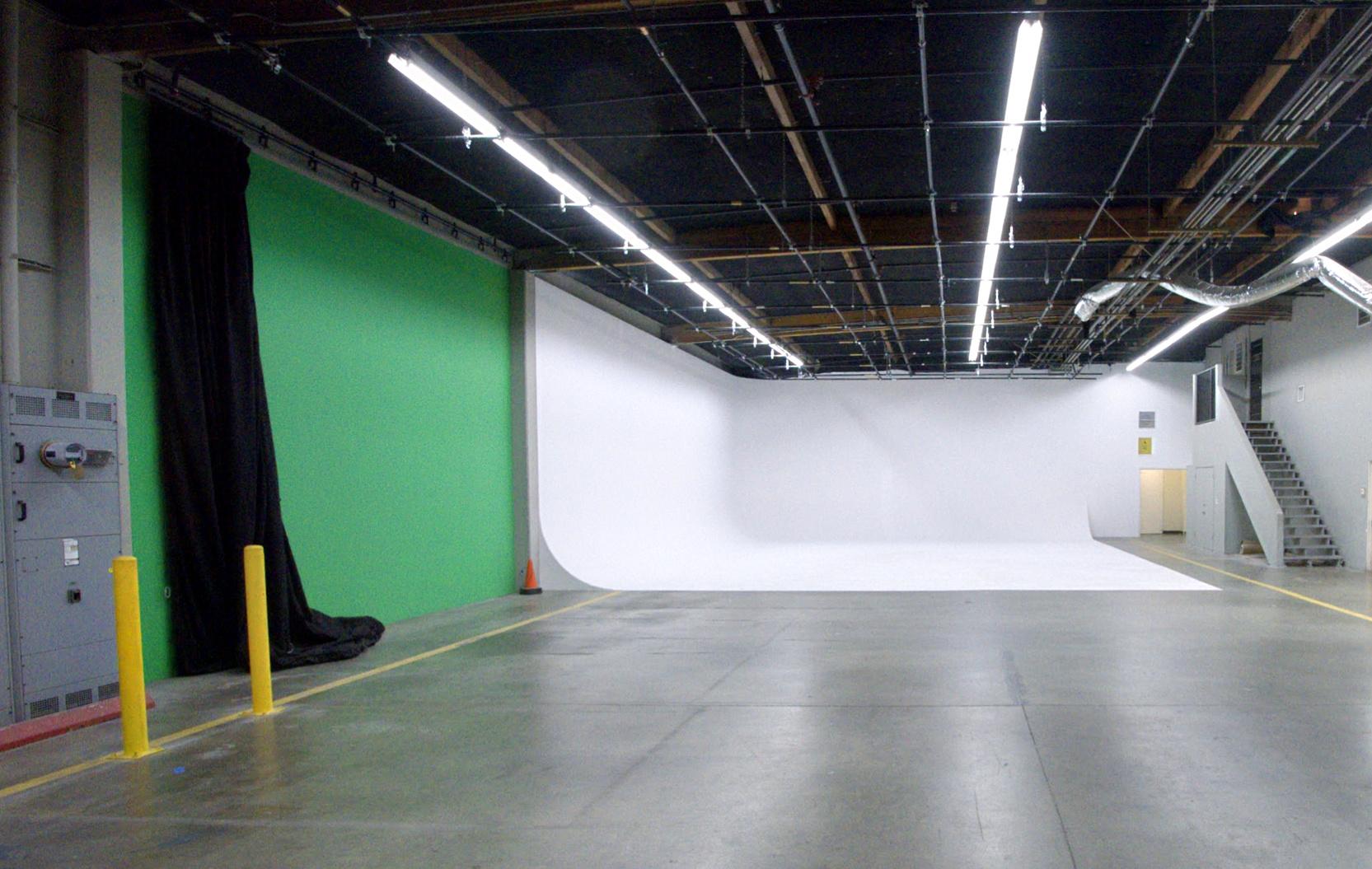 A photo and film studio with a large white cyclorama wall, adjacent green screen, and exposed ceiling at Studio 1 White Cyclorama & Green Screen.