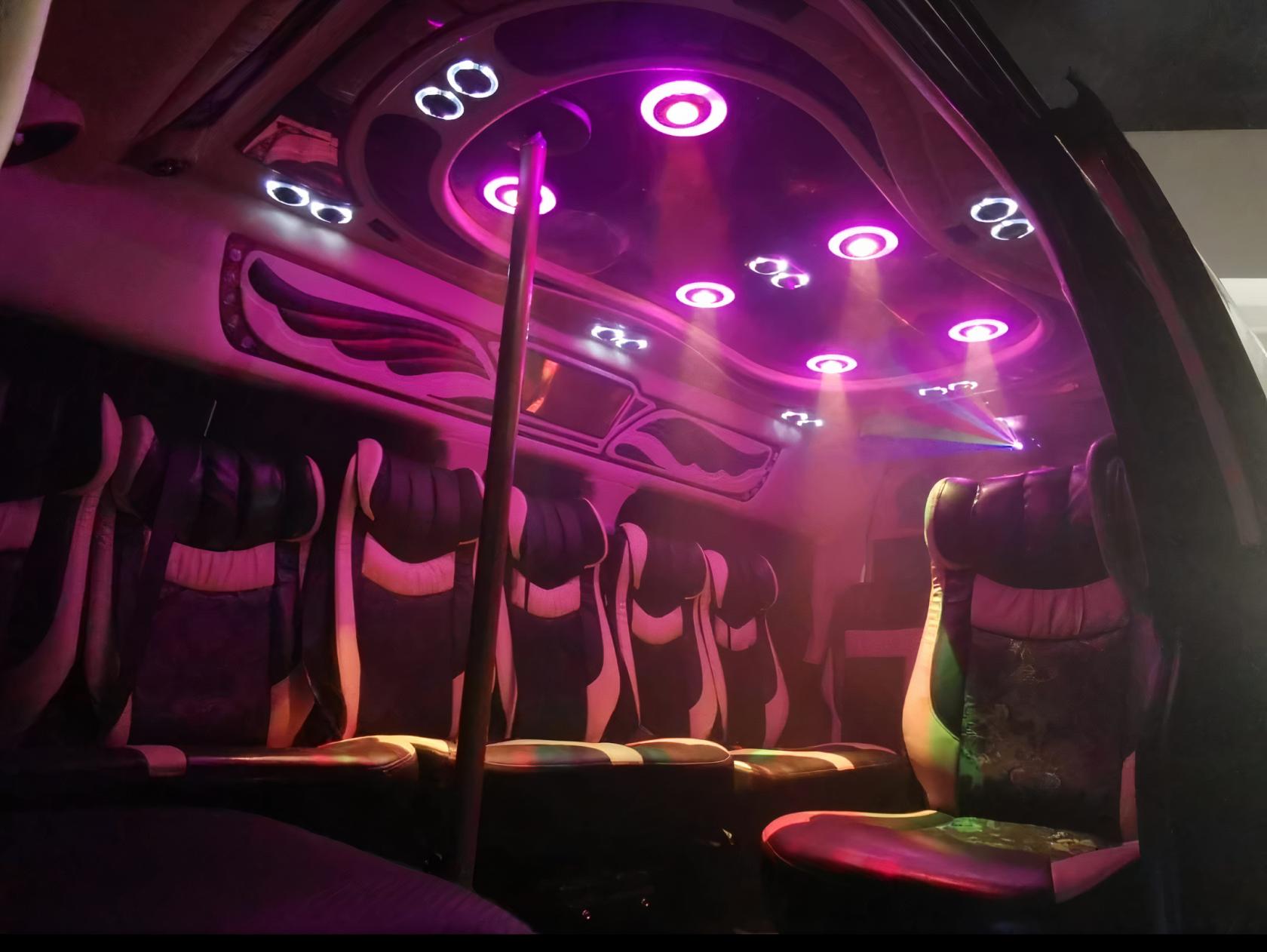 A party bus with leather seats, neon ceiling lights, and a central dance pole at Maxi Cab Singapore.