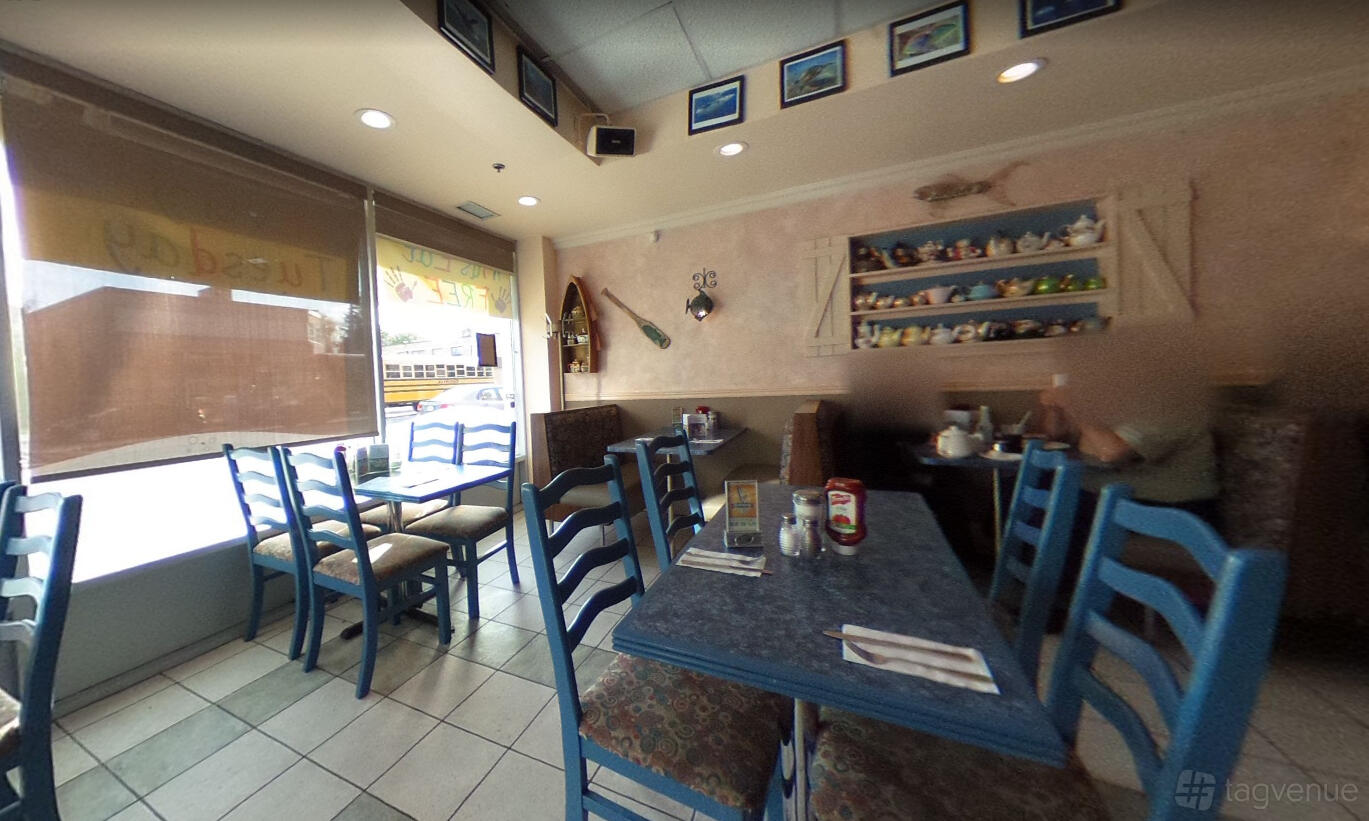 A restaurant with blue wooden chairs, nautical decor, and shelves displaying teapots at Kingsway Fish And Chips.