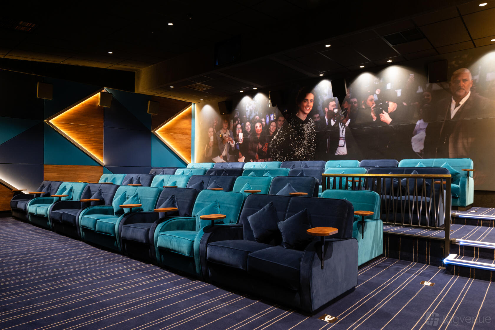 An auditorium with tiered velvet seating, individual armrest tables, and a mural wall at Everyman Edinburgh.