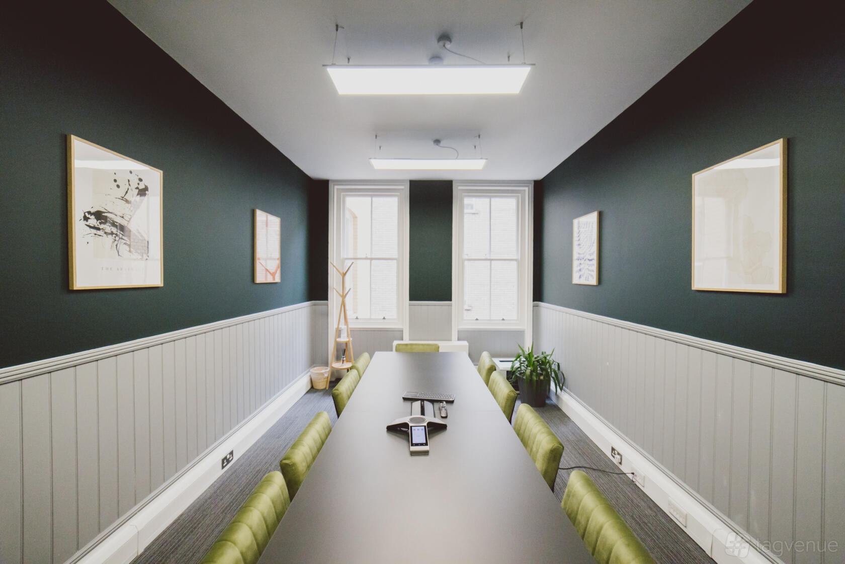 A meeting room with dark green walls, framed artwork, a long table, and natural light at Clement Rooms by Spacemade.