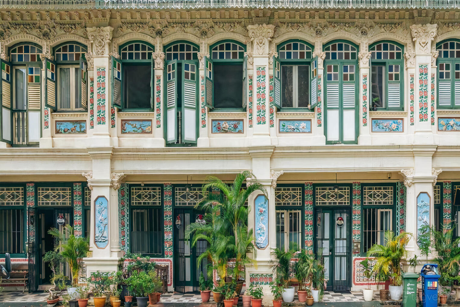 An apartment building with ornate pastel-faced facade, arched windows, and potted plants at Petain Road.
