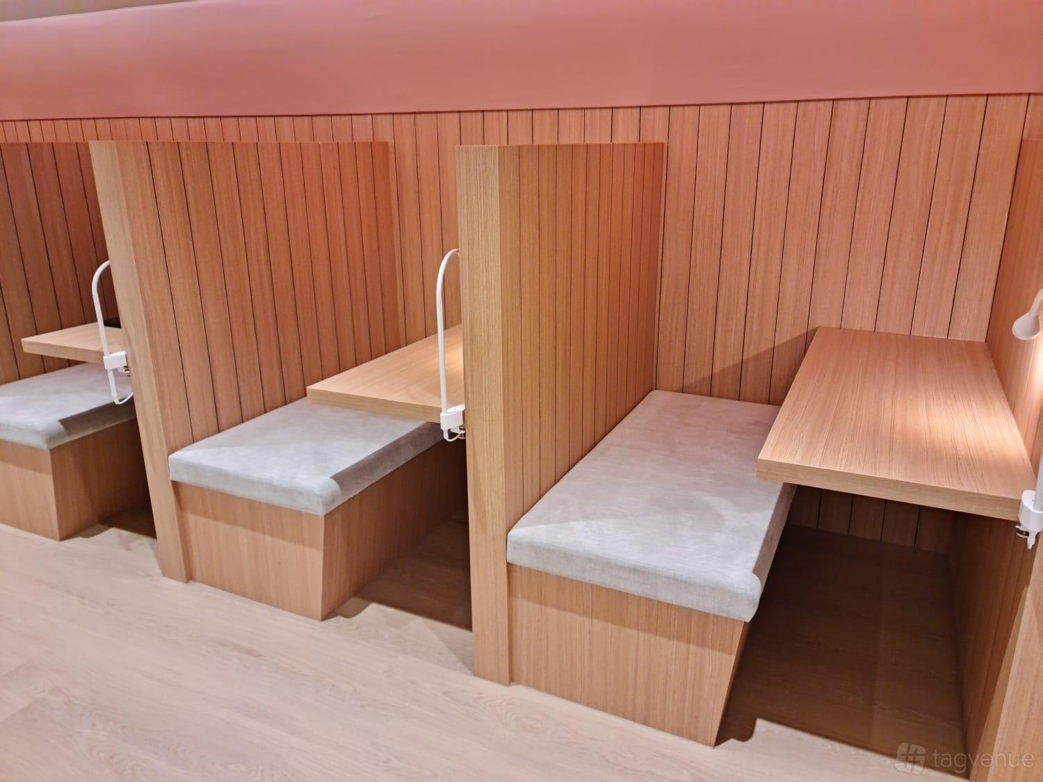A coworking space with individual wooden desks, cushioned bench seating, and desk lamps at N9 Offices (City Hall).
