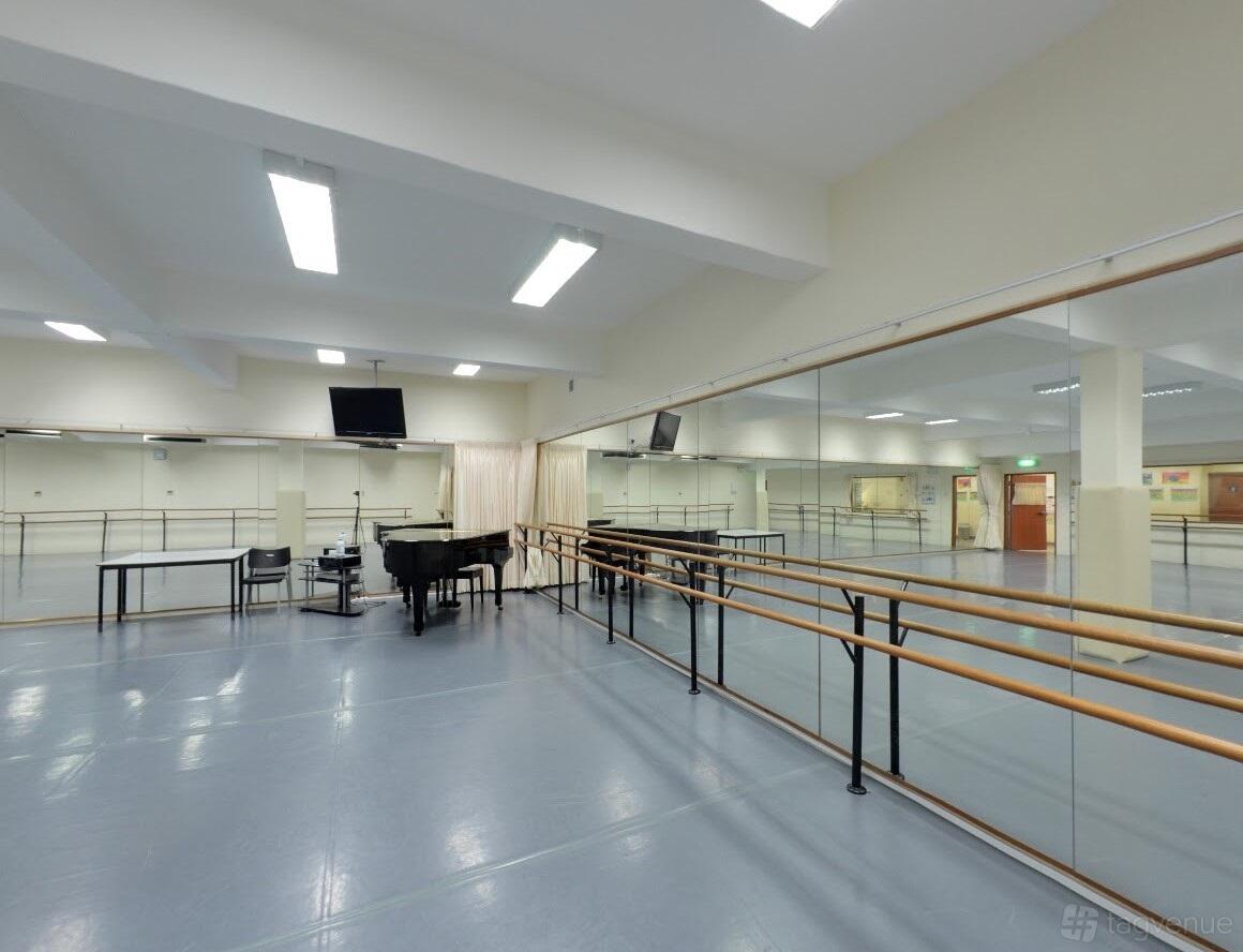 A dance studio with wall-length mirrors, ballet barres, a piano, and bright overhead lighting at Crestar School of Dance @ Marine Parade.