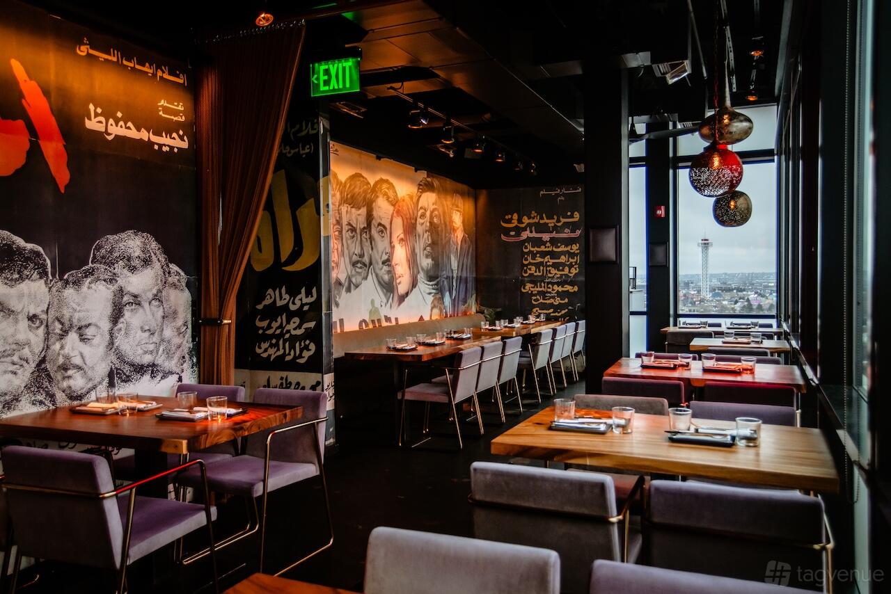 An event space in a restaurant with mural-covered walls, pendant lights, and floor-to-ceiling windows at EL Five.