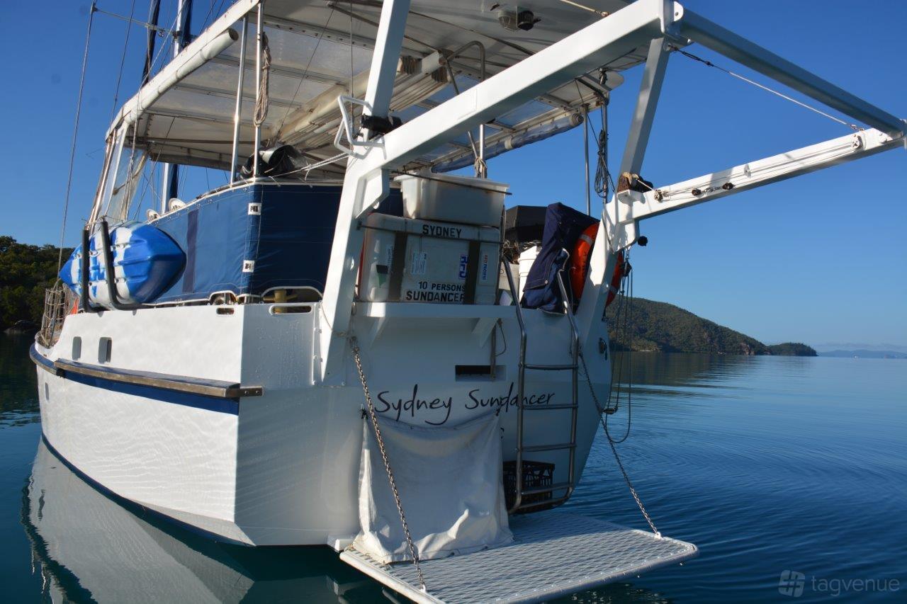 A boat with a shaded rear deck, ladder access to the water, and life jackets displayed on Sydney Sundancer.