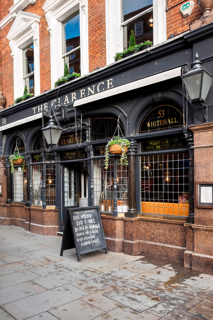 A pub with ornate black-framed windows, hanging baskets, and a chalkboard menu at The Clarence Whitehall.