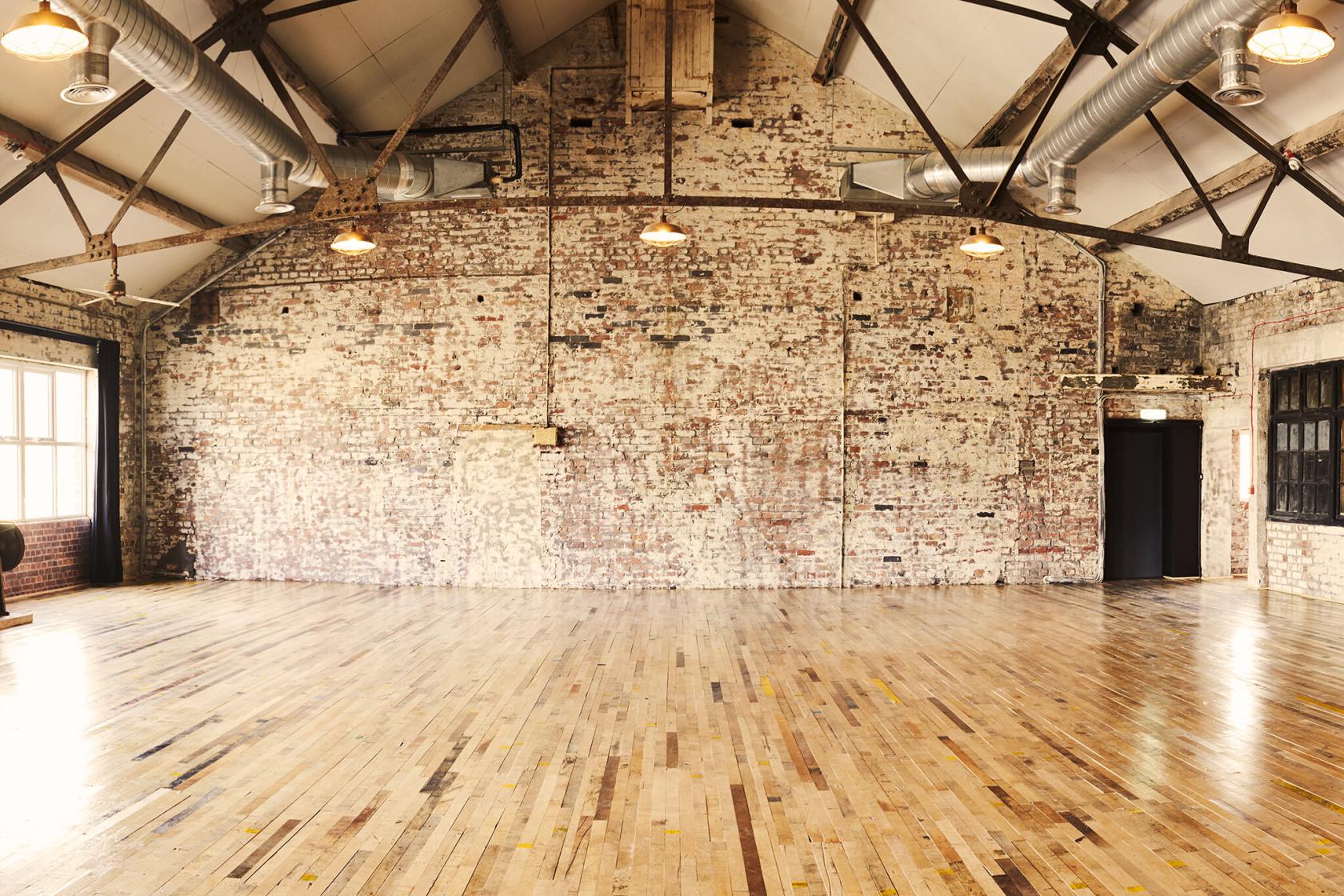 A photo and film studio with exposed brick walls, industrial lighting, and hardwood floors at Scale, Liverpool.