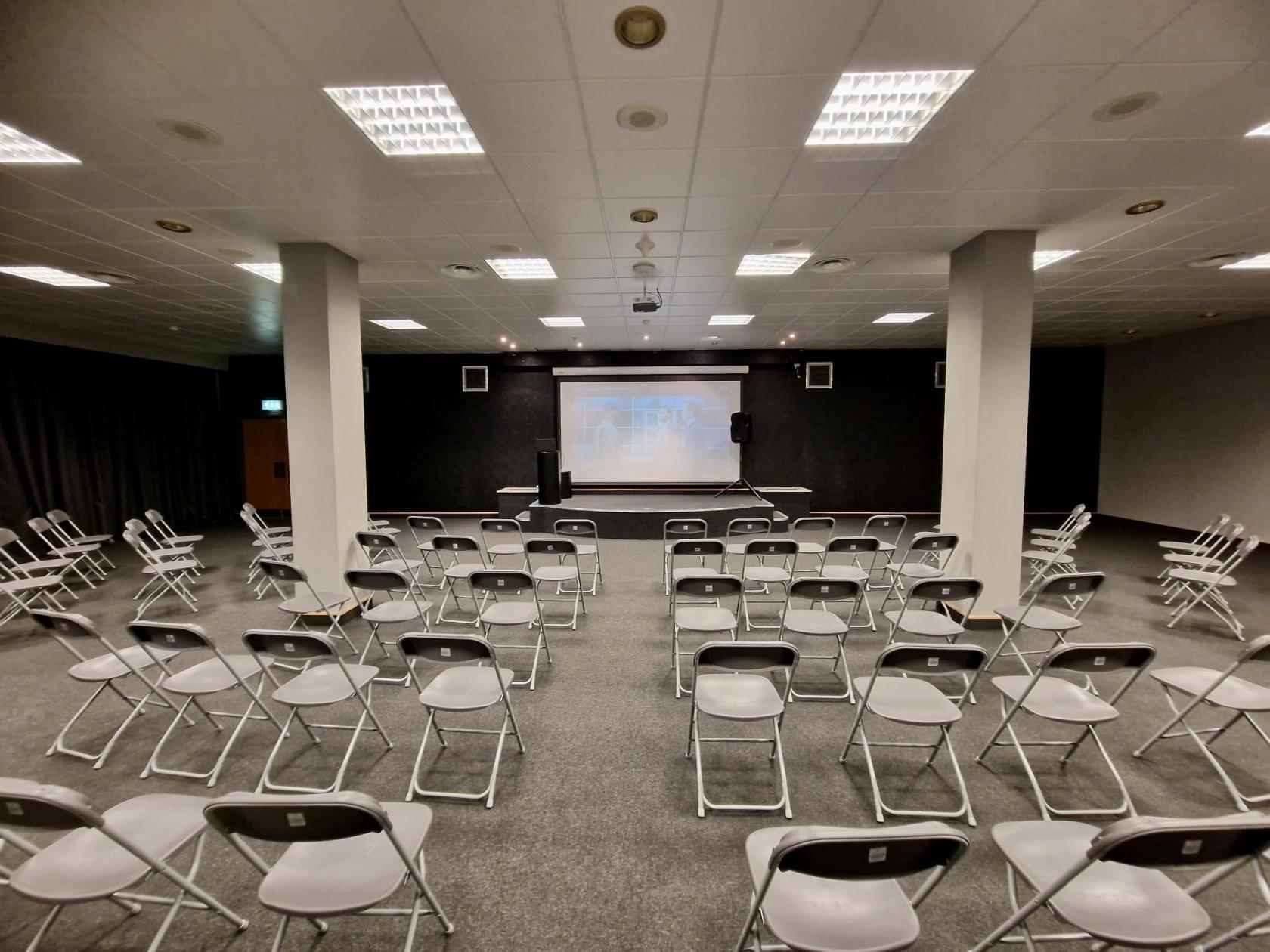 An auditorium with rows of metal chairs facing a projection screen and speakers at London North Studios.