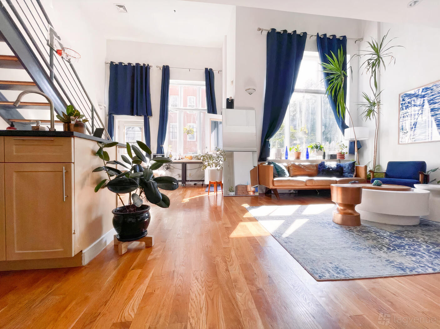 A loft with floor-to-ceiling windows, hardwood floors, and blue curtains at Martin's Loft Studio.