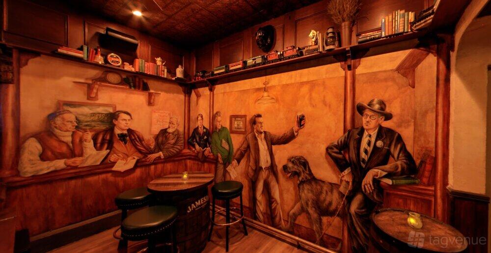 An event space in a pub with mural-painted walls, candles on barrel tables, and shelves holding books at Chief Sullivan's.