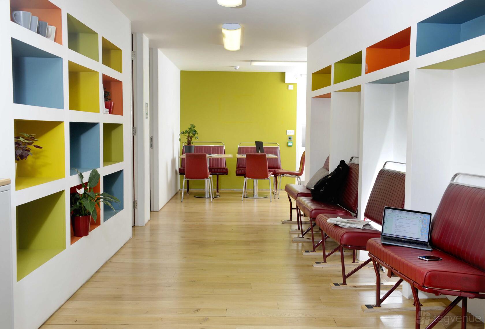 An event space with colorful open shelving, red chairs, and light wood flooring at The Melting Pot.