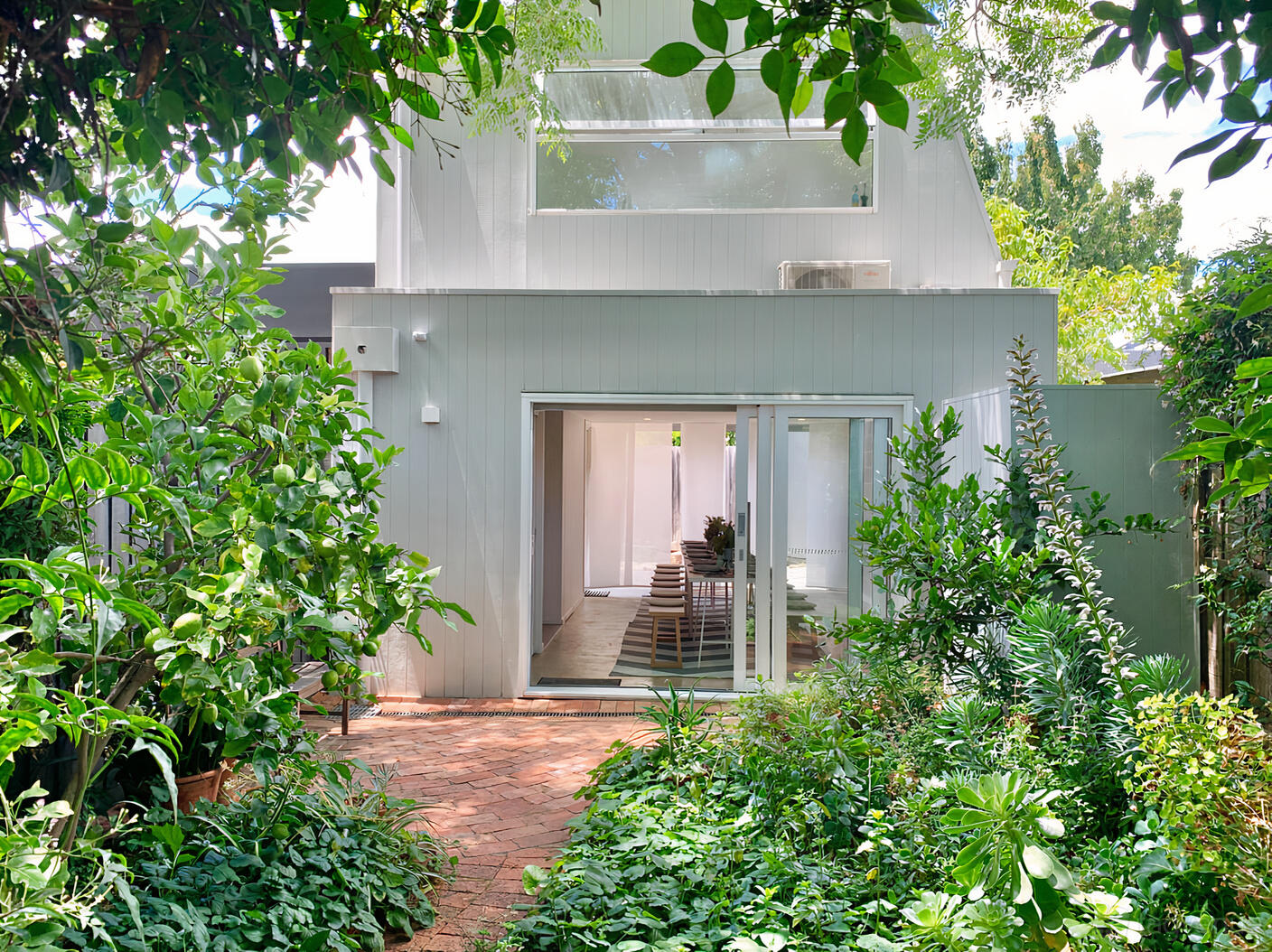 An apartment with glass doors opening to a brick patio, surrounded by lush greenery at Studio 58.