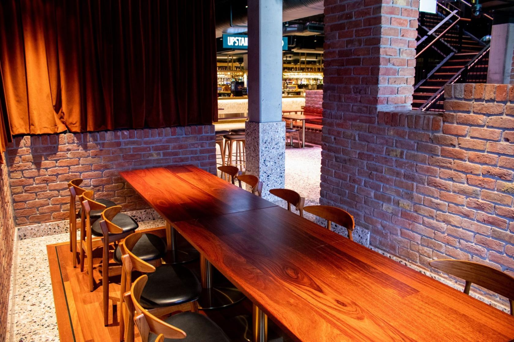 A dining room with a long wooden table, brick walls, and wooden chairs at The Sound Garden.