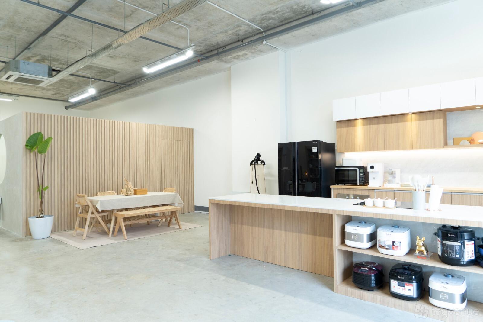 A kitchen studio with a long island, open shelving with appliances, and a dining table at Aydan.Co