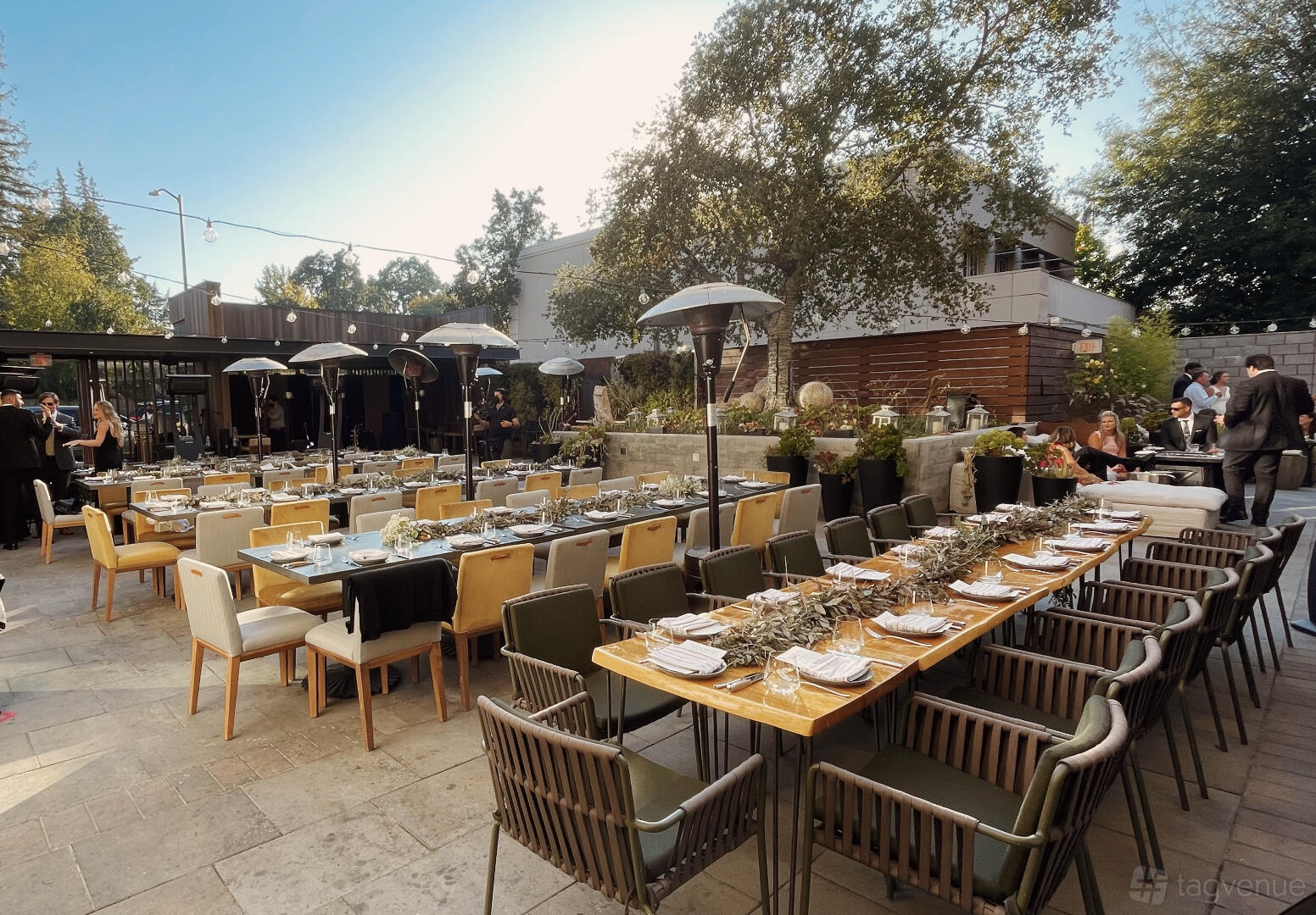 A hotel terrace with long dining tables, cushioned chairs, and outdoor heaters at Park James Hotel.