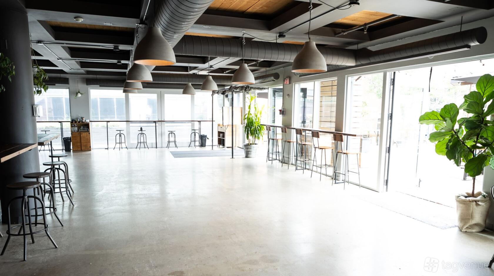 A cafe with concrete floors, large windows, pendant lighting, and a high-top counter at Boxcar Social - Harbourfront.