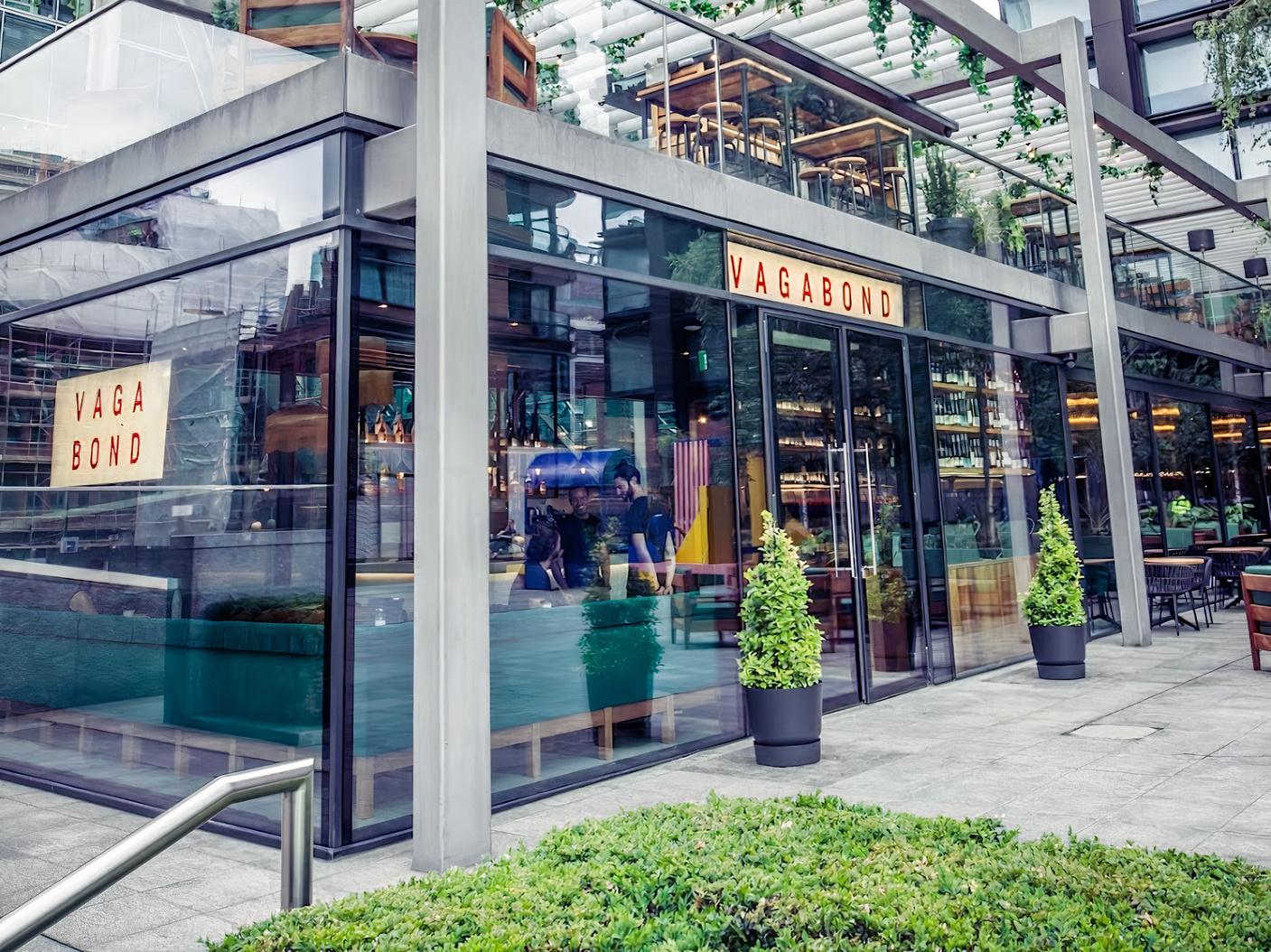 A modern pub with floor-to-ceiling glass windows and outdoor planters at Vagabond Shoreditch.