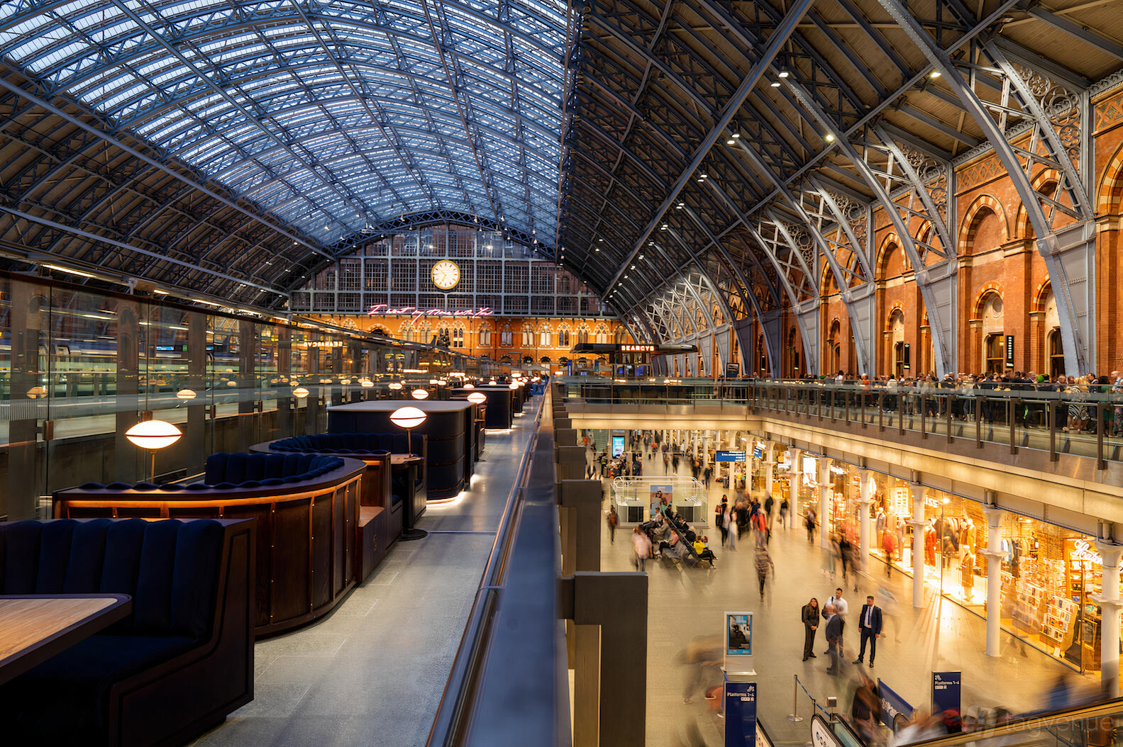 A restaurant event space with curved booth seating, globe pendant lighting, and a glass roof at St Pancras by Searcys.