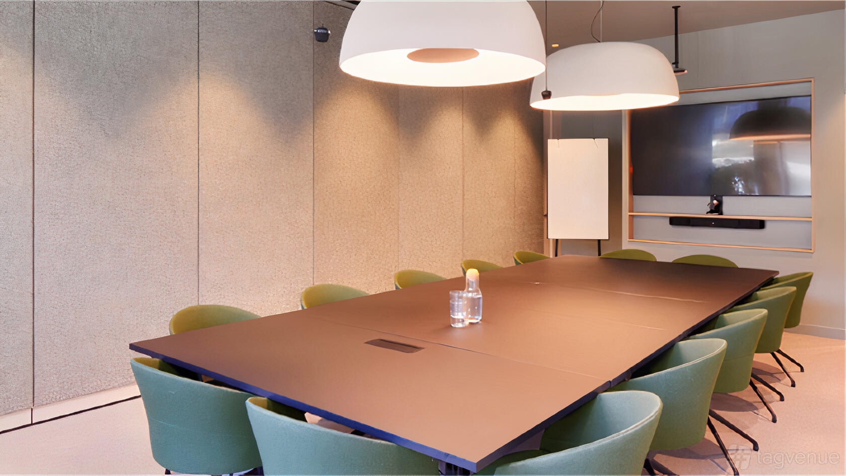 A meeting room with a long black conference table, green chairs, large pendant lights, and a wall-mounted screen at Storey Club Broadgate.