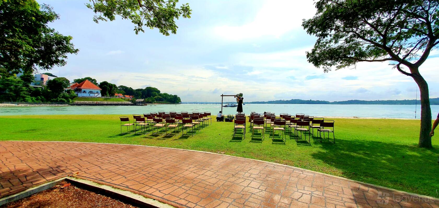 A beachside lawn with rows of chairs arranged for a ceremony and an arch overlooking the sea at Little Island Brewing Co. Beach Solemnisation.