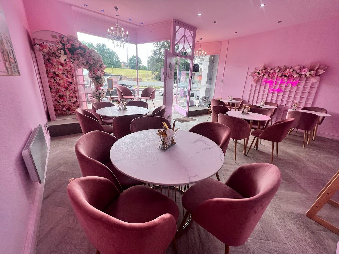 A function room in a cafe with pink velvet chairs, marble tables, and flower walls at Beauty and The Feast.