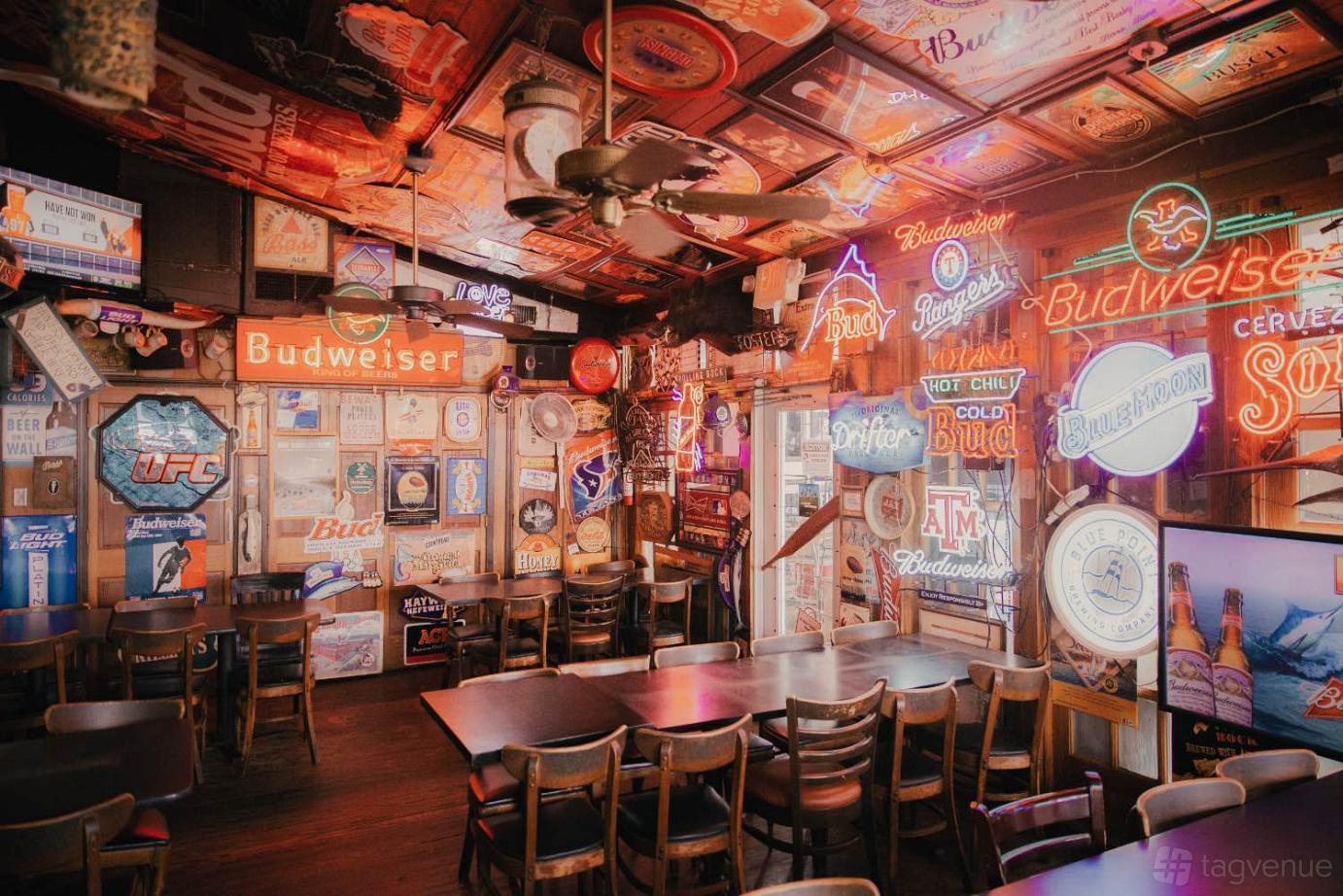 A bar with neon beer signs, wooden tables, and memorabilia covering the walls and ceiling at St. Pete’s Dancing Marlin.