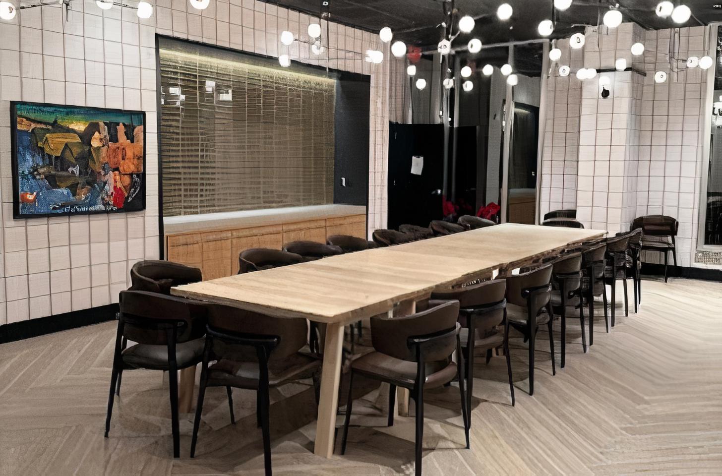 A dining room with a long wooden table, dark chairs, pendant lights, and tiled walls at The Chancery Market.