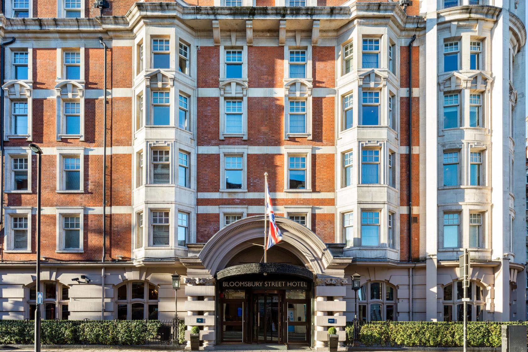 A hotel with a red brick facade, arched entrance, and British flags at Radisson Blu Hotel, London Bloomsbury.
