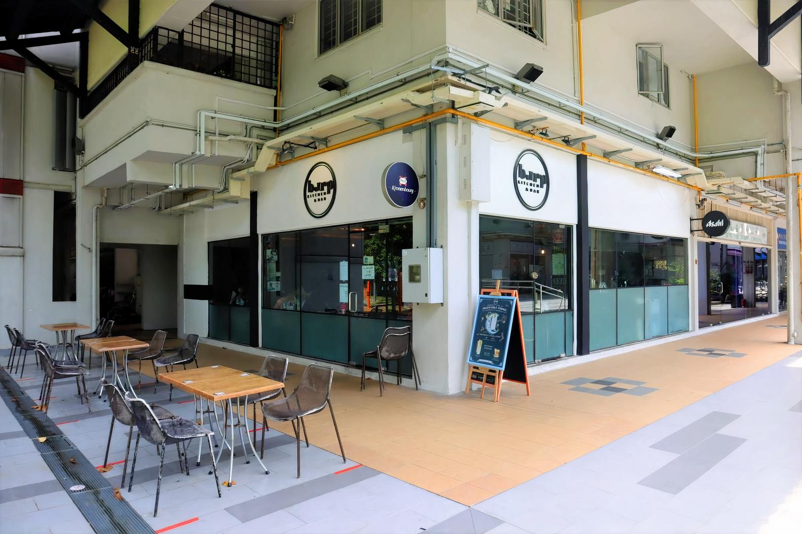 A pub with outdoor seating, wooden tables, and large windows at Burp Kitchen & Bar - Bedok Reservoir.