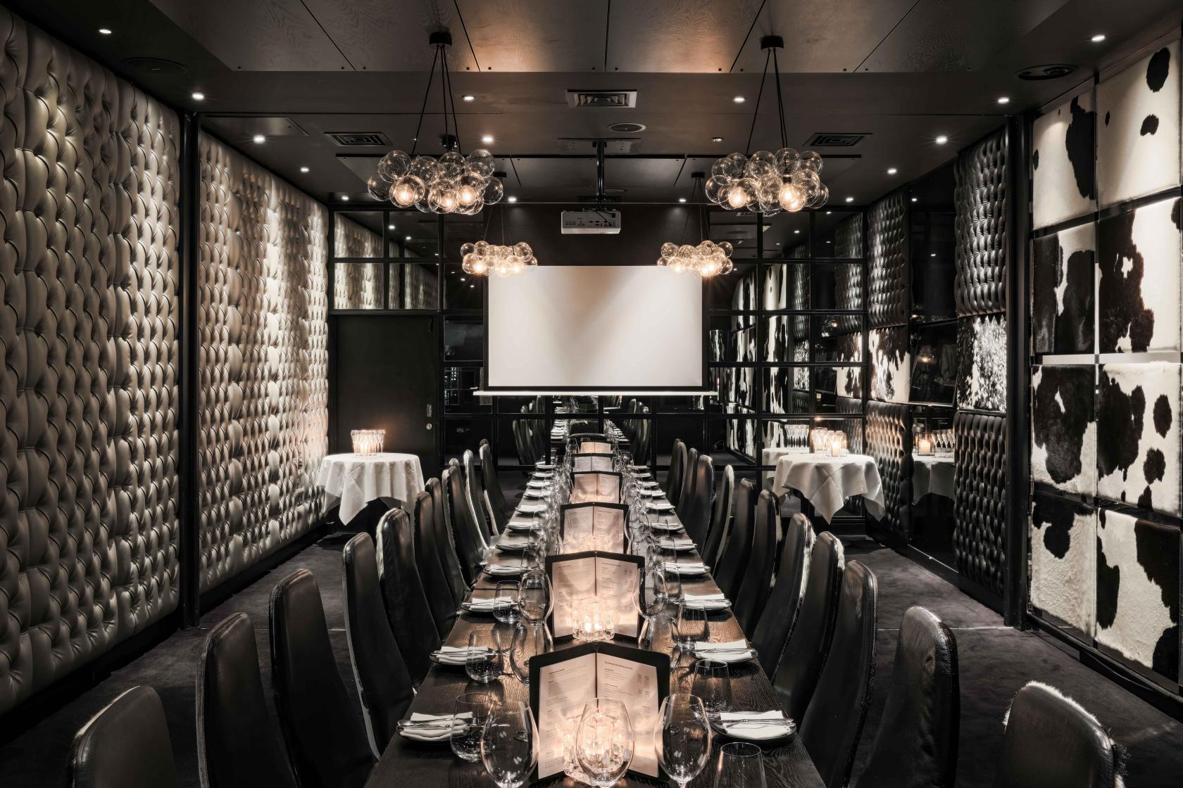 A dining room with tufted leather walls, mirrored panels, and a long banquet table set for guests at Gaucho Piccadilly.