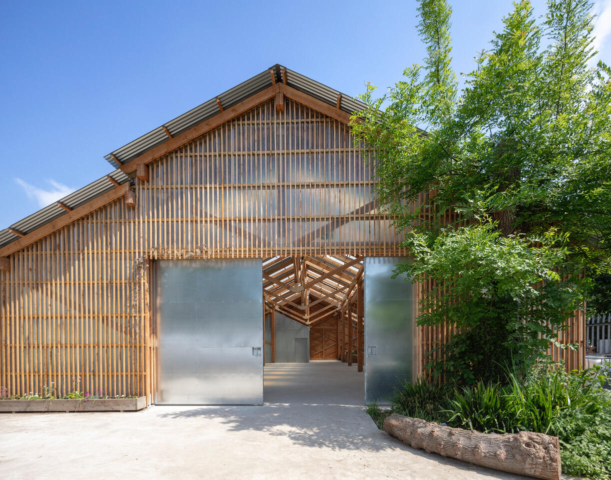 A barn with metal sliding doors, wooden slat exterior, and a pitched roof at Oasis Farm Waterloo.