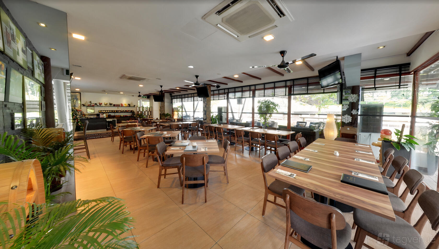 A restaurant with wooden tables, modern chairs, large windows, and potted plants at Cheval Equestrian Walk.