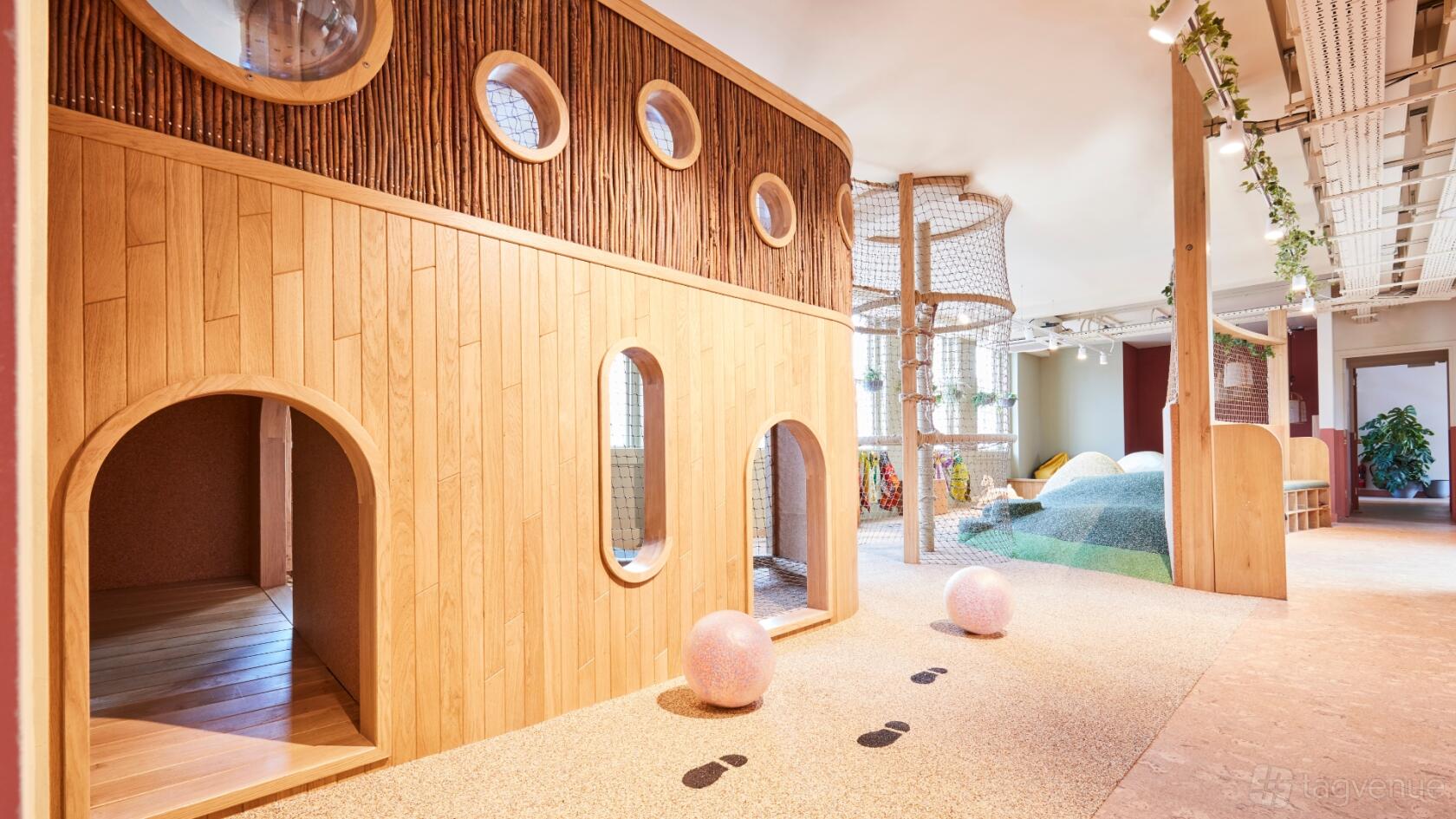 An event venue with a wooden playhouse, circular windows, and climbing structures at b_together.