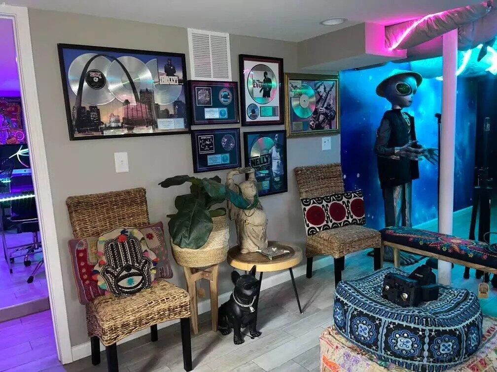 A recording studio lounge with wicker chairs, framed platinum records, colorful wall art, and eclectic sculptures at GGA Studio.