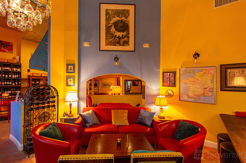 A restaurant lounge area with red leather armchairs, colorful walls, framed artwork, and warm ambient lighting at Aquitaine.