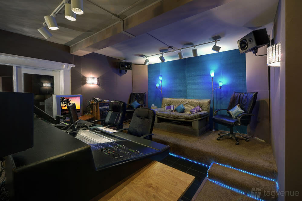 A recording studio with a mixing console, soundproofed walls, and blue accent lighting at Private Island Audio.