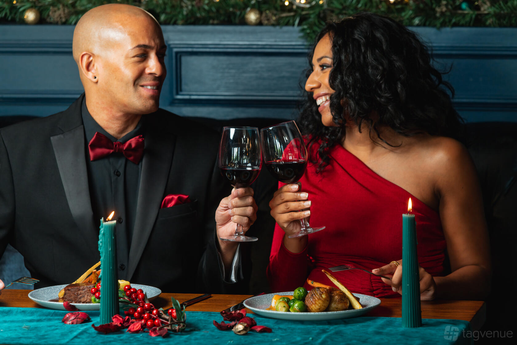 A bar in a restaurant with dark blue panel walls, festive greenery, and couples dining by candlelight at Banyan Newcastle.