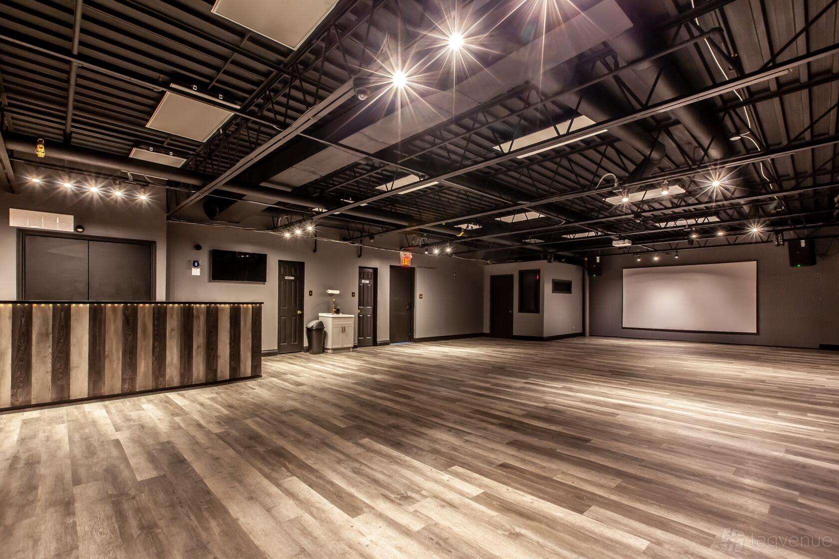 An event venue with exposed black ceilings, wood-look flooring, and a striped reception counter at Freedom Venue.