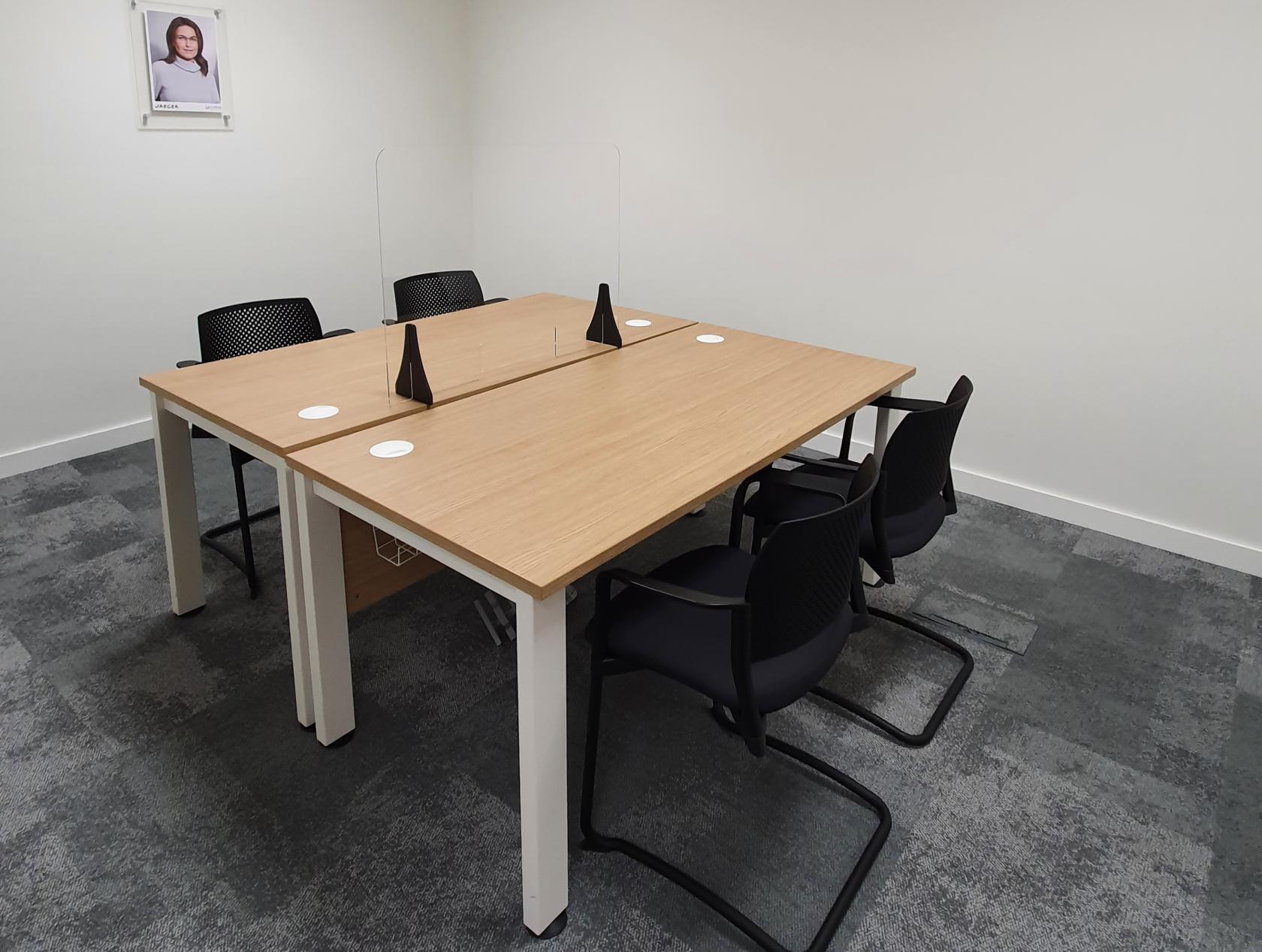 An event venue with a boardroom featuring a shared wooden table, black chairs, and acrylic desk dividers at ABDO National Resource Centre.