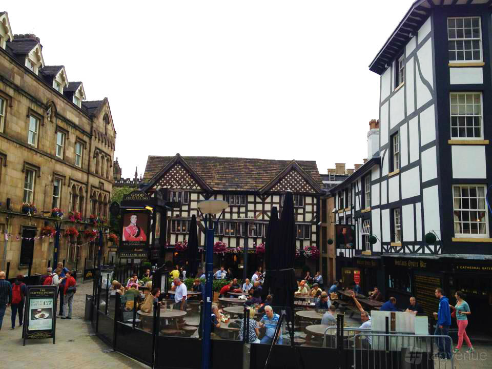 A pub with half-timbered exterior, outdoor seating, and patrons enjoying drinks at The Old Wellington.