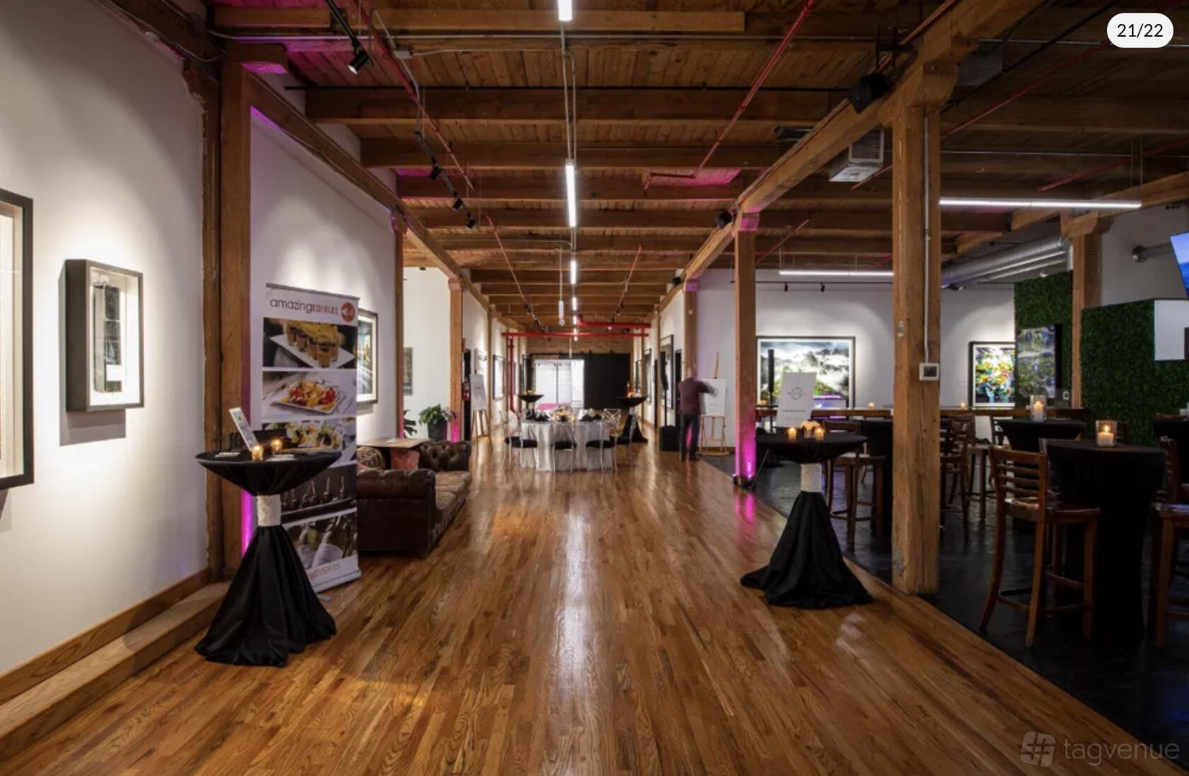 An event venue with polished wood floors, exposed wooden beams, and art-lined walls at Morgan Arts Complex.