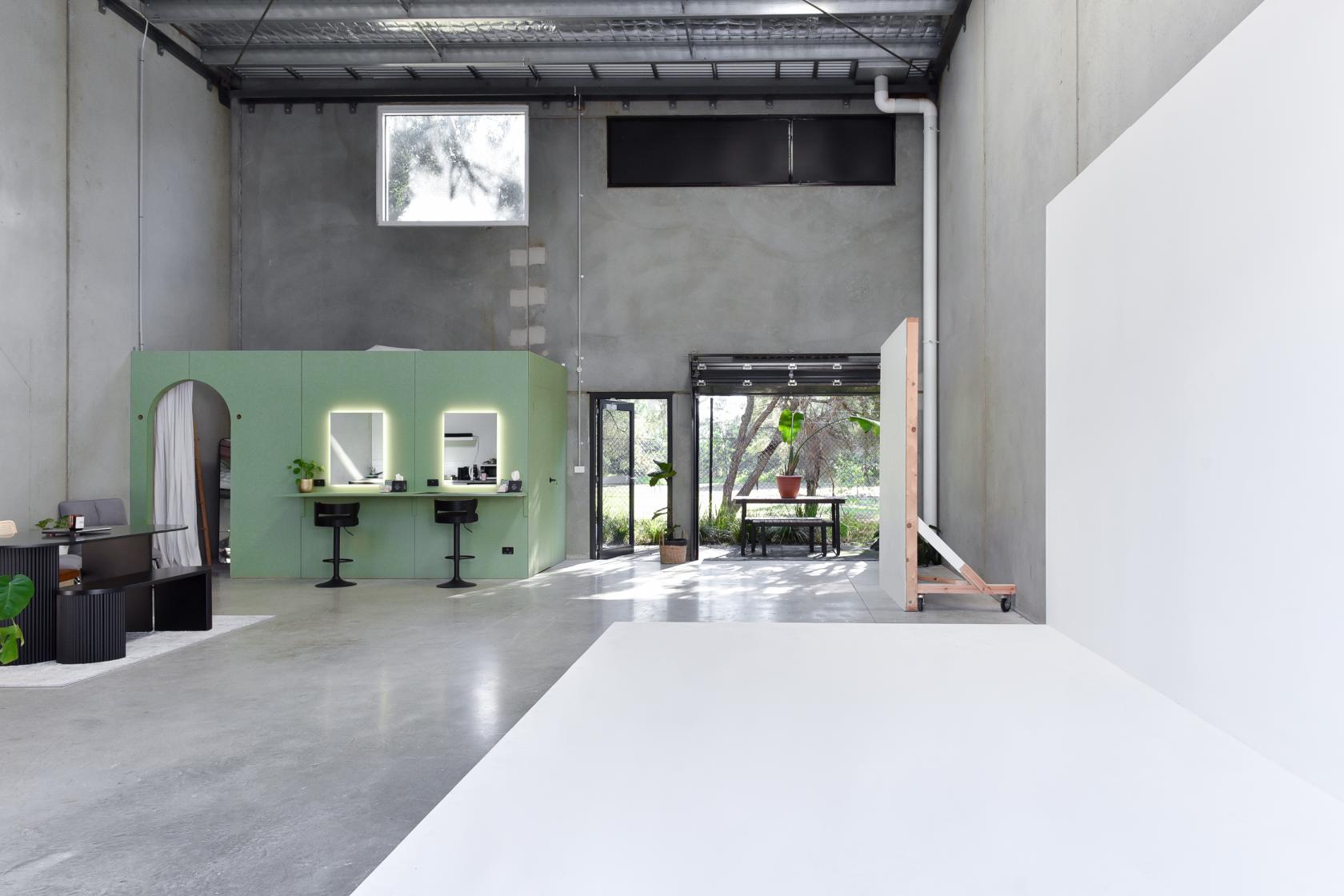 A photo studio with high ceilings, concrete walls, makeup stations, and a bright cyclorama at Bohemia Bay Studio.