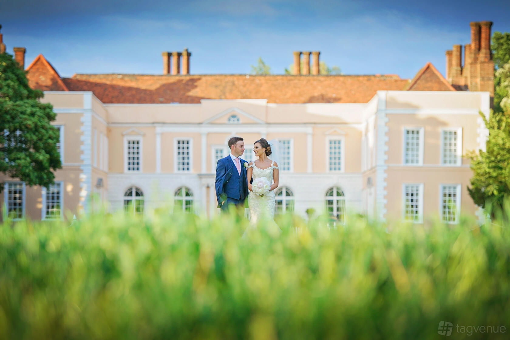 A historic hotel with a symmetrical façade, large windows, and manicured grounds at Hintlesham Hall Hotel.
