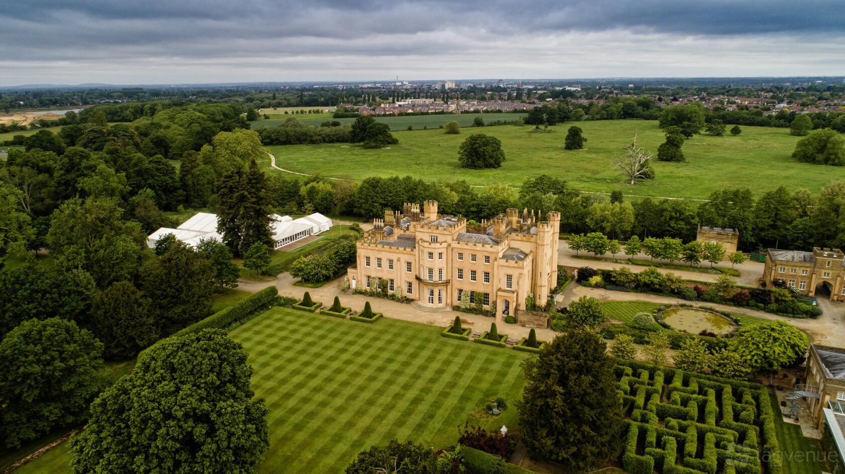 A versatile event space with a white marquee tent set beside manicured lawns and a historic manor at Ditton Manor Marquee.