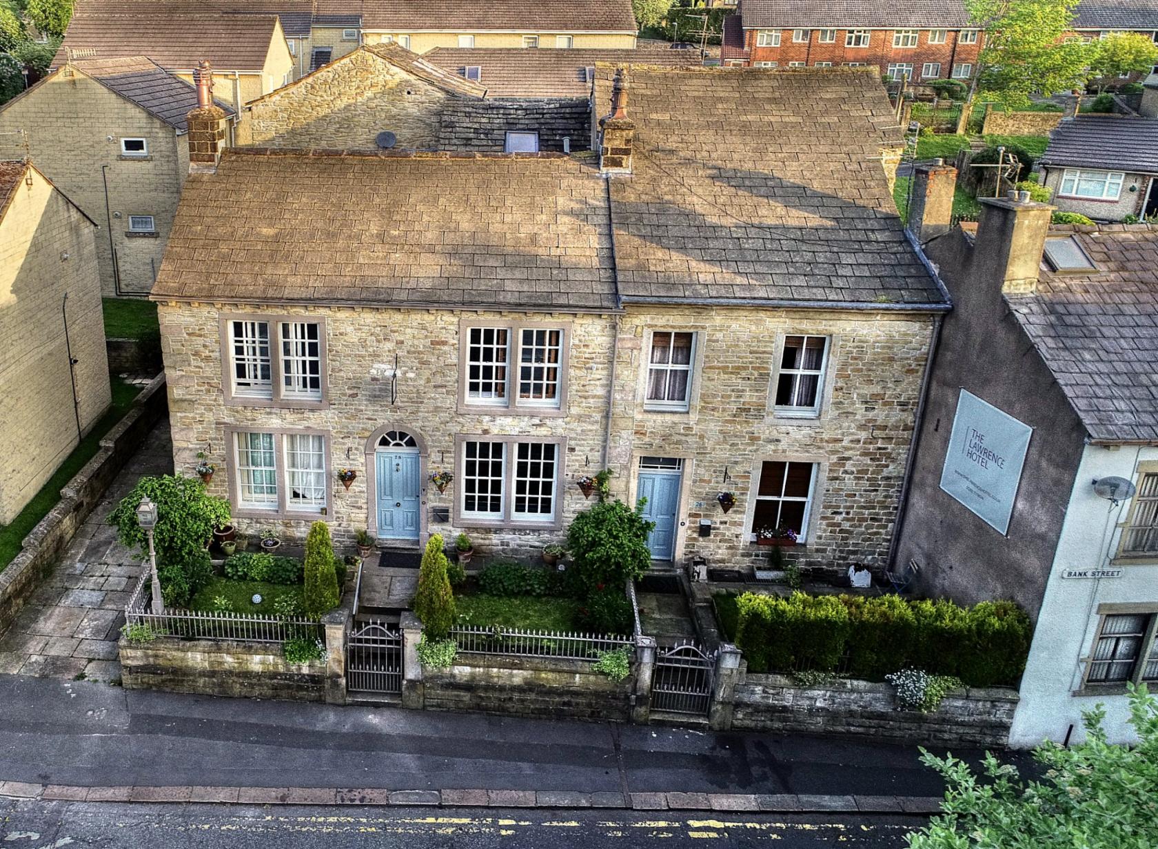 A hotel with a stone façade, large sash windows, and a small garden with shrubs at The Lawrence Hotel.