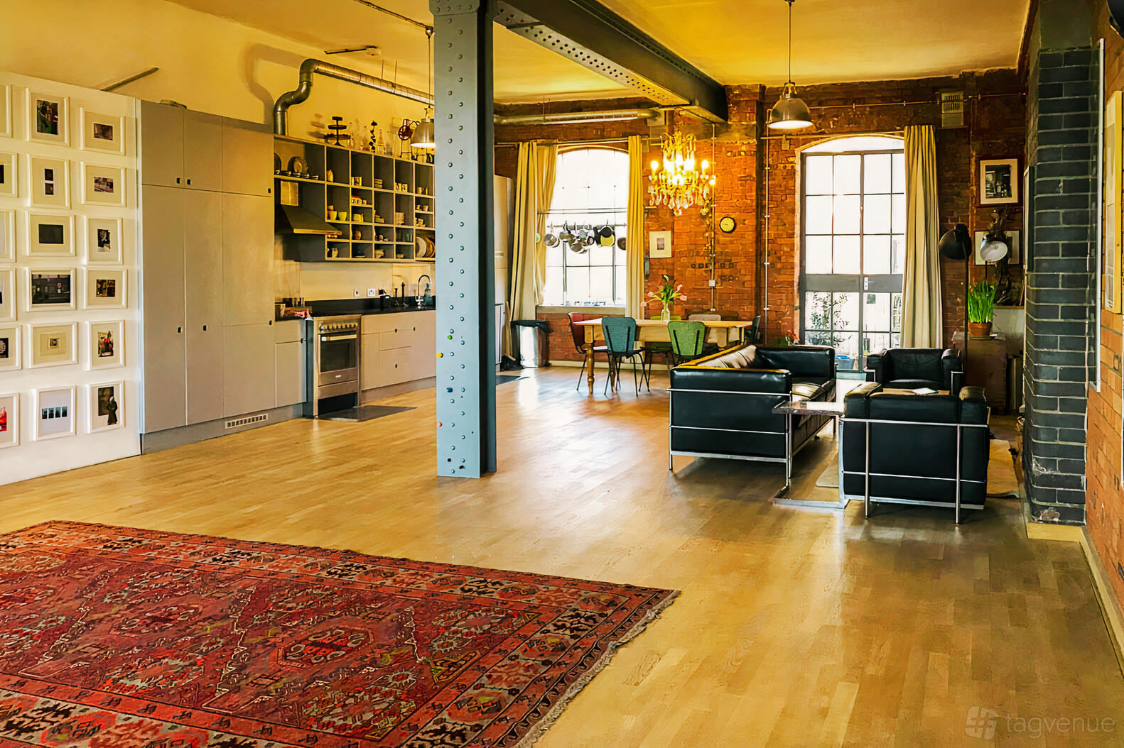 A loft with exposed brick walls, large arched windows, leather lounge seating, and open kitchen at Woolly Mammoth spaces.